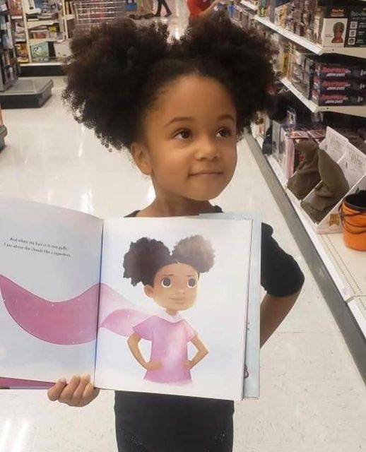 Foto de niña afro sosteniendo ilustración de niña afro con capa